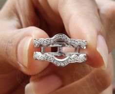 a person holding a ring in their hand with diamonds on the inside and outside of it