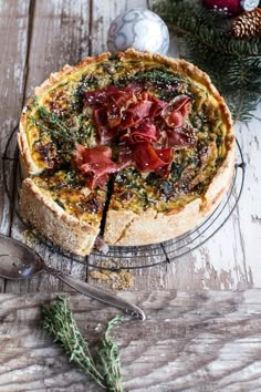 a quiche with bacon, cheese and herbs on a wire rack next to christmas decorations