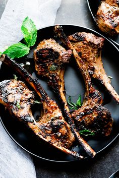 grilled lamb chops on a black plate with mint garnish