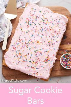 a cake with pink frosting and sprinkles is on a cutting board