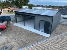 an overhead view of a metal building with a red car parked in the driveway next to it