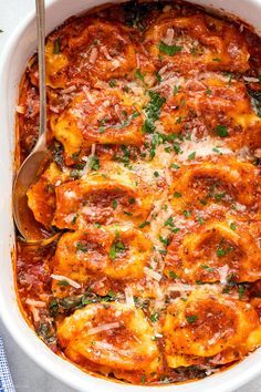 a white casserole dish filled with pasta and sauce, garnished with parsley