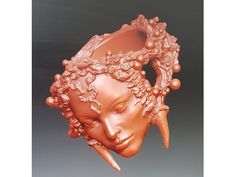 a ceramic sculpture of a woman's head with horns and flowers in her hair