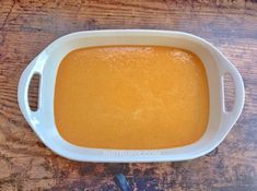 a white bowl filled with yellow liquid on top of a wooden table