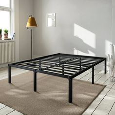 a metal bed frame sitting on top of a carpeted floor next to a lamp