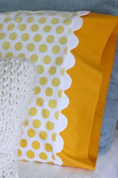 a yellow and white polka dot pillow sitting on top of a bed next to a stuffed animal