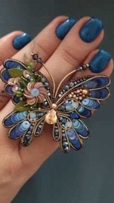 a woman's hand holding a blue butterfly brooch