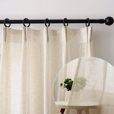 a round mirror sitting on top of a wooden table next to a curtain with black metal rods