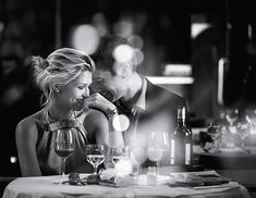 a man and woman sitting at a table with wine glasses