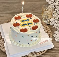 a birthday cake on a table with a lit candle