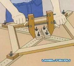 a person is working on a wooden frame with two hands and one hand holding the board