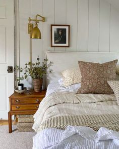 a bed with white sheets and pillows on top of it next to a wooden dresser