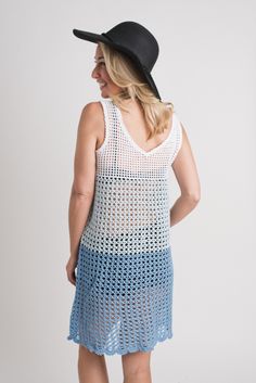 a woman wearing a blue crochet dress and black cowboy hat standing in front of a white background