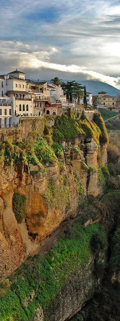 an old town on the edge of a cliff with grass growing in front of it