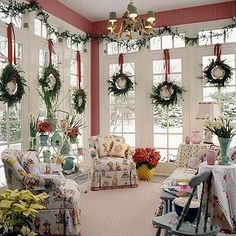 a living room decorated for christmas with wreaths on the windows and flowers hanging from the ceiling