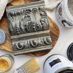 various types of paint and brushes on a wooden board next to some other items that are being used