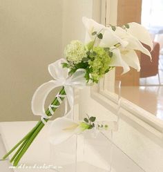 a bouquet of white flowers sitting on top of a table next to a mirror in a room