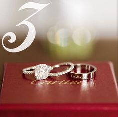 two wedding rings sitting on top of a red box with the number 3 in it