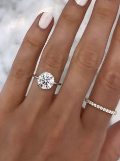 a woman's hand with two different rings on her fingers and one ring in the middle