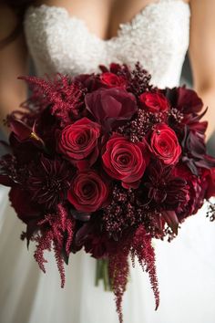 a bride holding a bouquet of red flowers