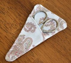 a pair of scissors sitting on top of a piece of cloth covered in paisley print