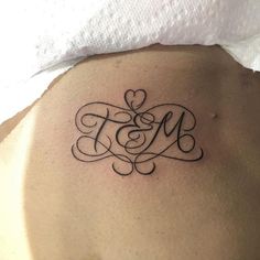 a woman's lower back tattoo with the letter m on it