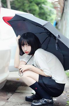 a woman kneeling down with an umbrella over her head