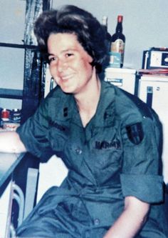 an old photo of a woman in uniform sitting at a table with bottles on it