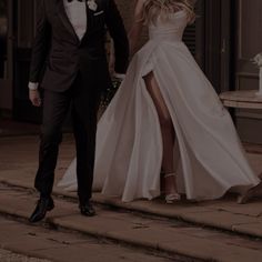 a man in a tuxedo and a woman in a wedding dress walking down the street