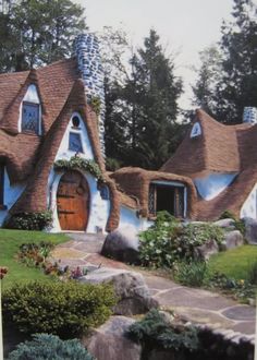 an image of a house with blue and white paint on the front, surrounded by greenery