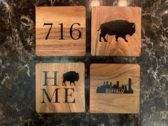 four wooden coasters with the words home and buffalo on them, sitting on a marble countertop