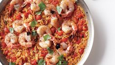 a pan filled with shrimp and rice on top of a white table next to a fork