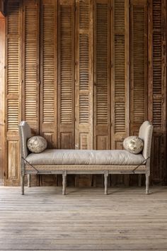 an old wooden bench with two pillows on it in front of a wood paneled wall