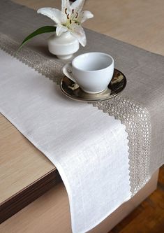 a white flower sitting on top of a table next to a cup and saucer