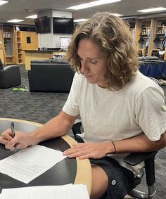 a person sitting at a table writing on paper