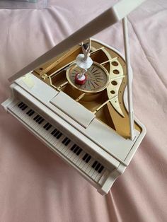 an old fashioned musical instrument is sitting on a pink bed sheet with a white cover