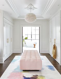 a living room with white walls and wooden floors, a large rug on the floor