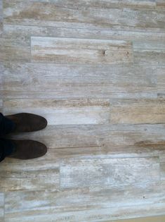 a person standing on top of a wooden floor next to a pair of brown shoes