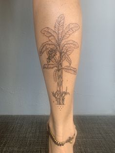 a woman's foot with a tattoo on it and a plant in the middle