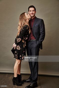 a man and woman kissing each other in front of a gray background