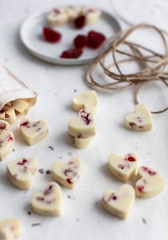 small pieces of white chocolate with raspberry toppings next to a plate of strawberries