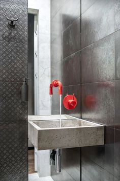 a bathroom sink sitting under a mirror next to a wall mounted faucet with red handles