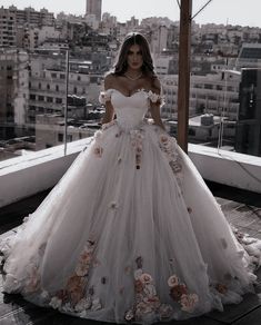 a woman in a wedding dress standing on top of a building with flowers all over it