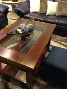 a living room filled with furniture and a glass top coffee table in front of a blue couch