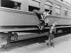 two children standing on the side of a train car with their hands in the windows