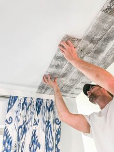 a man is painting the ceiling in his living room with blue and white paint on it