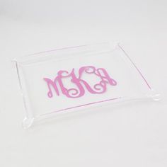 a clear acrylic tray with pink monogrammed letters