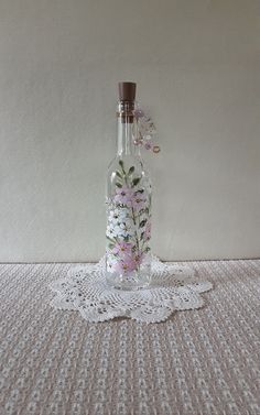 a glass bottle with flowers in it sitting on a doily