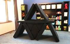 a black chair sitting on top of a carpeted floor next to a book shelf