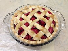 a pie with latticed crust and strawberries in it on a glass platter